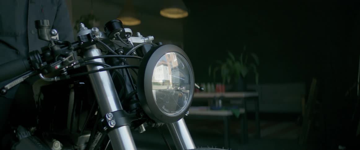 The motorcycle is sitting in the dark garage