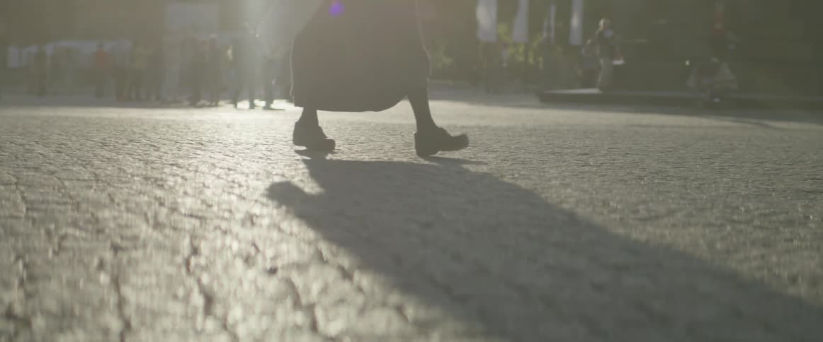 People are walking along the cobblestone on a sunny day