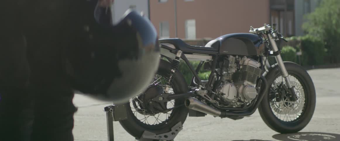 A person is holding his helmet near his motorcycle