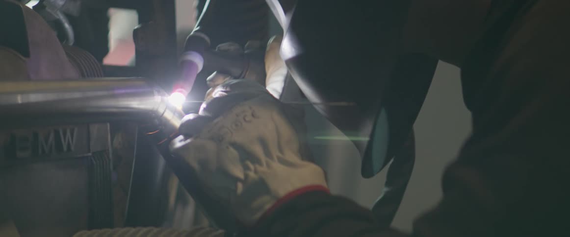 A man is welding an exhaust pipe on a motorcycle