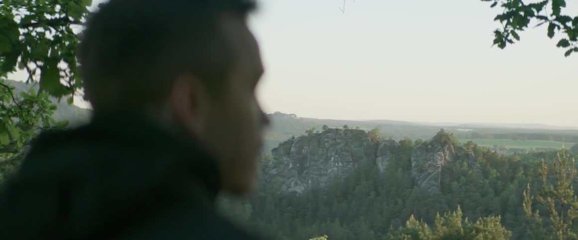 A man is looking out at the view from the mountain top