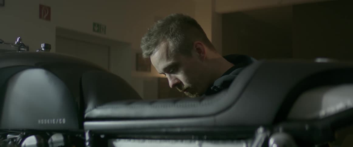 Man stands next to a motorcycle indoors