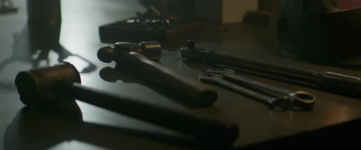 Several tools such as a hammers and wrenches are laying on a table