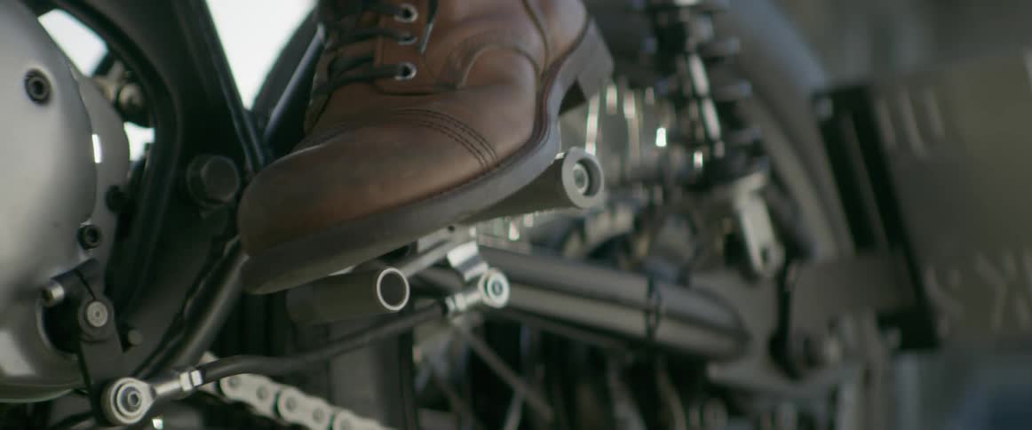 Man pressing on a motorcycle shifter with his boot to put it into first gear