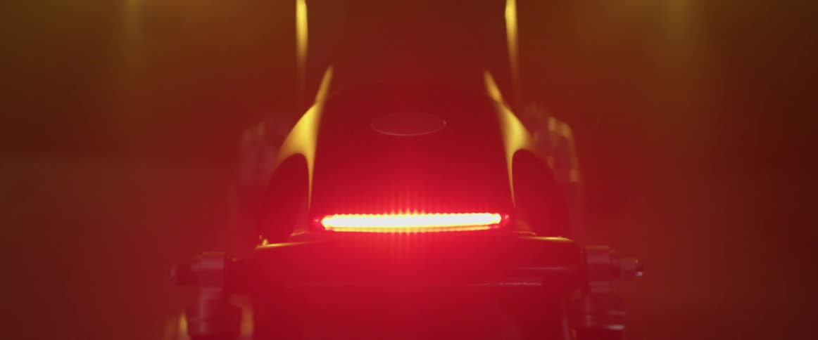 A motorcycle starting up at night looking at the tail lights