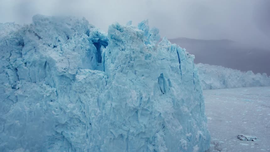 A blue iceberg stands tall over the water