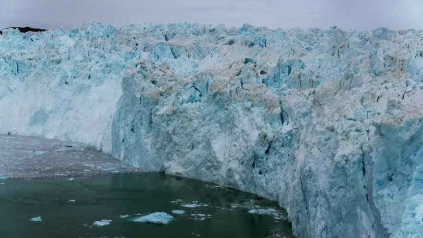Ice and debris float in the ocean at the base of a glacier
