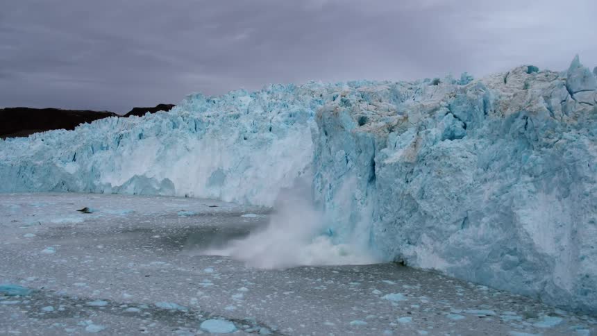 Snow falls off of a glacier and crashes to the ground