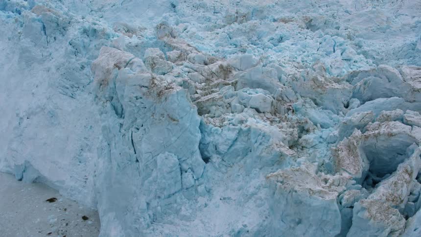 Ice and debris float in the ocean at the base of a glacier