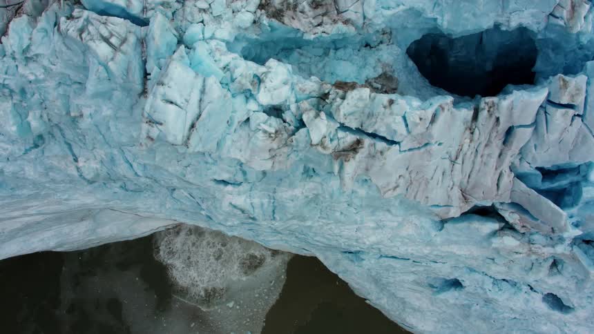 Snow and ice calves off a glacier causing ripples in the ocean