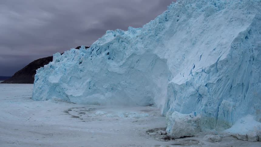 Ice falls off an iceberg formation into the water