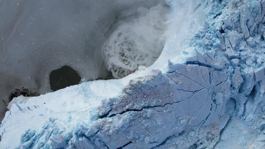 Ice falls off an iceberg formation into the water