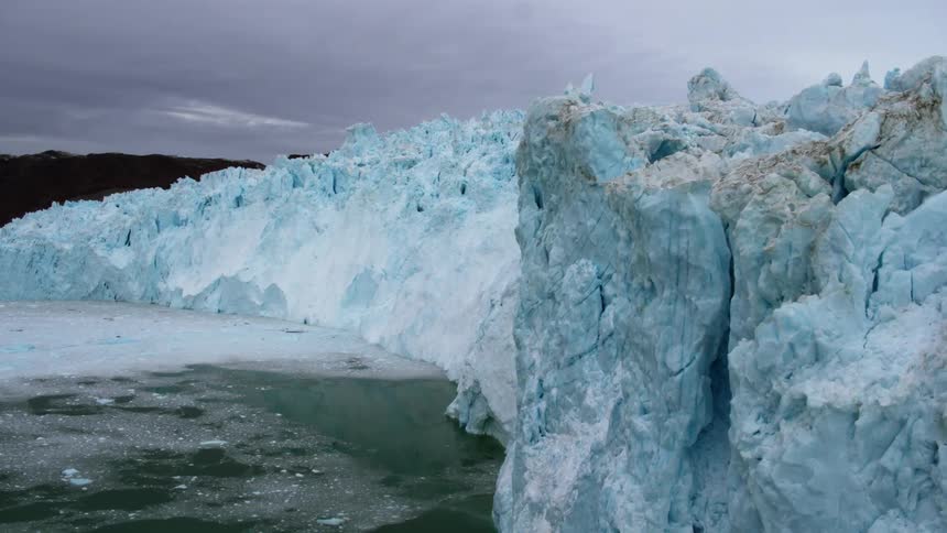 The long wall of ice is blue with some dirt on it