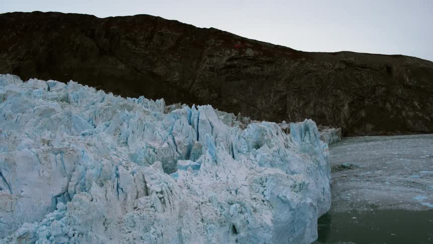 A helicopter flies above mountains and an iceberg