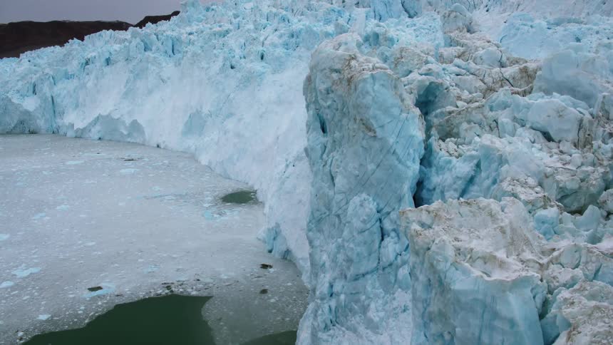 A large wall of ice is being flown over by a helicopter