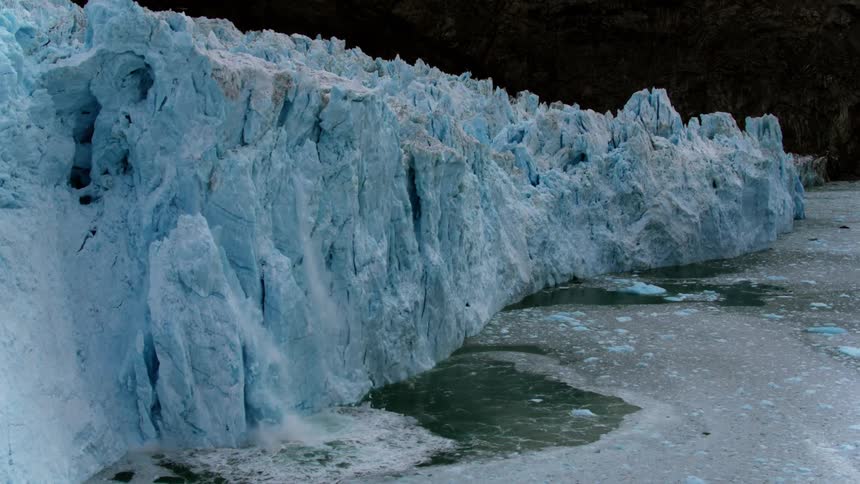 Ice falls off an iceberg formation into the water