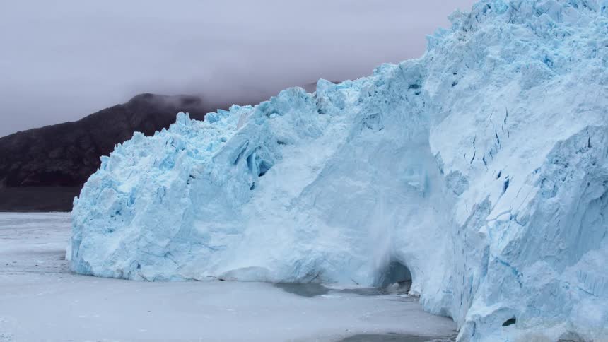 Snow falls from glacier and crashes into water
