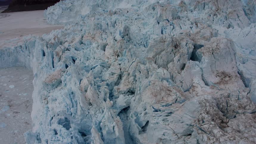 A tall ice formation towers over the water