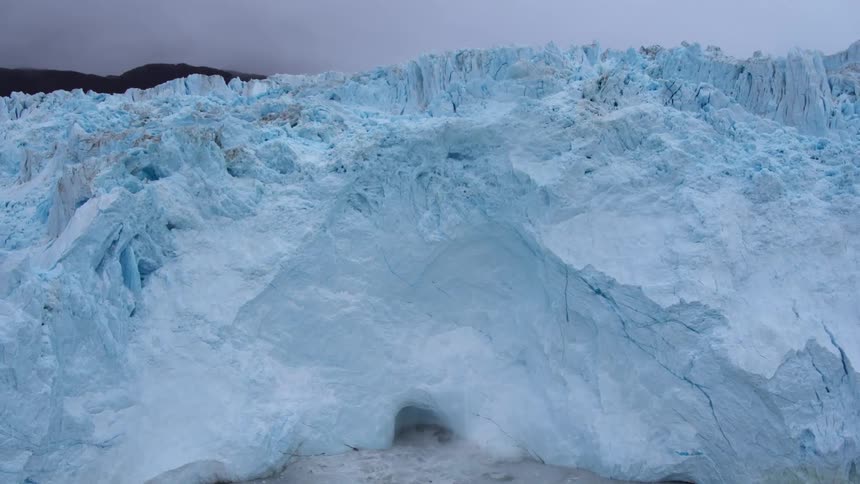 Ice falls off an iceberg formation into the water