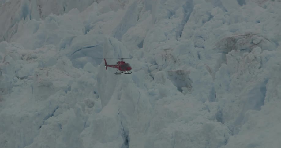 Helicopter flies in snowy mountains