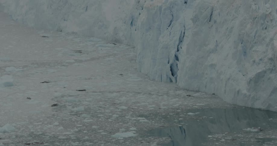 The water has ice floating all over by the ice wall
