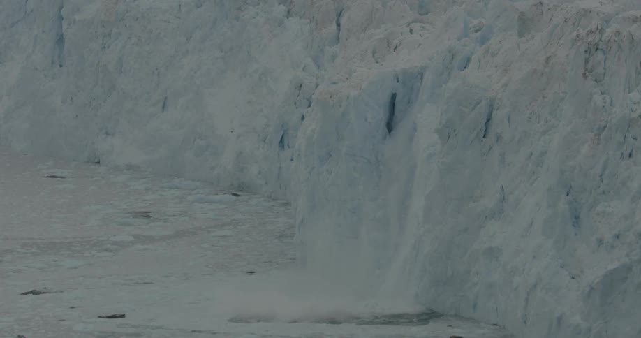 Ice breaks off an iceberg and splashes into the ocean