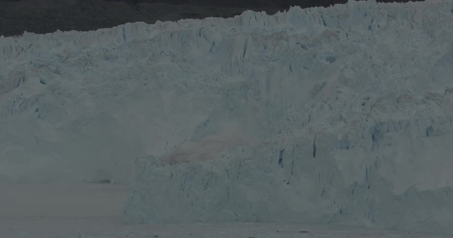 An iceberg is calving from a glacier and falling into the ocean