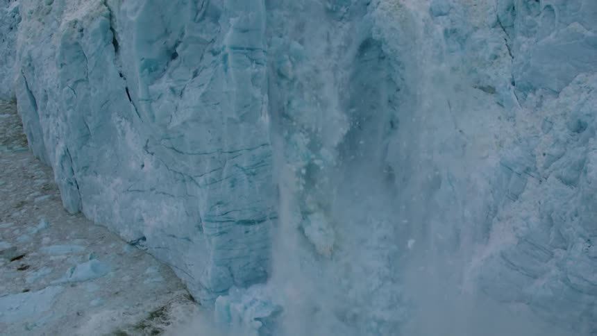 Ice cracks and falls from a glacier