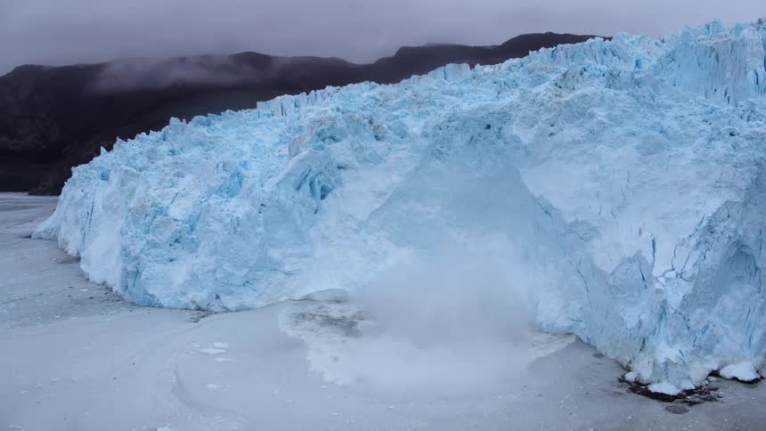 Large piece of ice falling off glacier into ocean