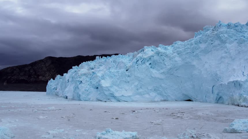 The water is frozen around the large blue iceberg