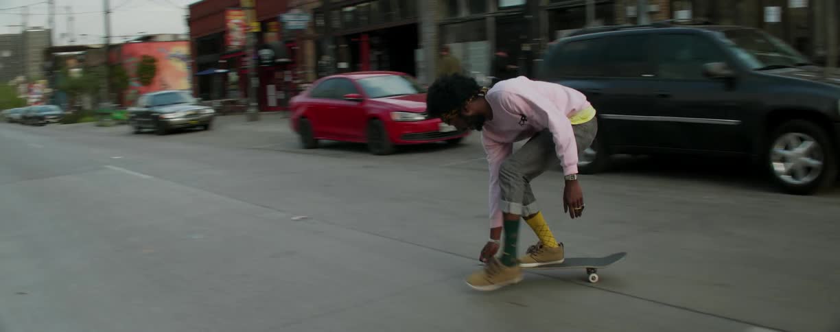 A man is skating through the street and into a parking lot
