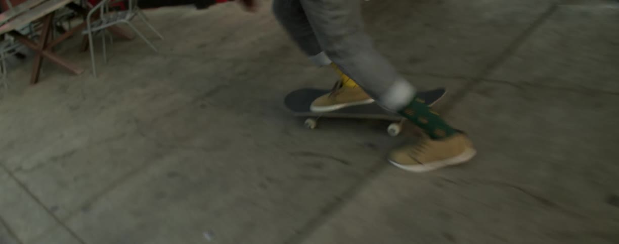 A kid is skateboarding down the street and jumped over a chair