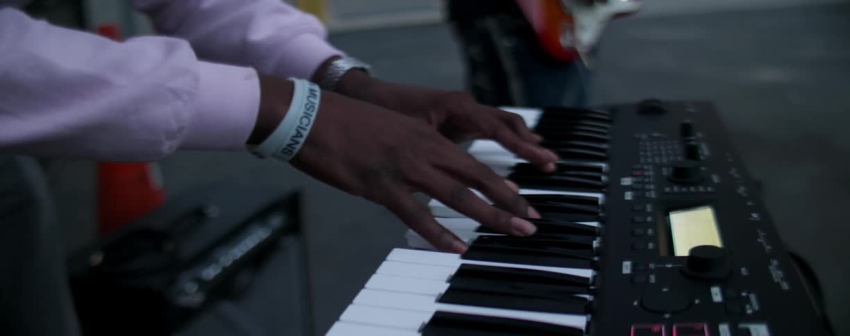 Man plays keyboard next to a guitarist