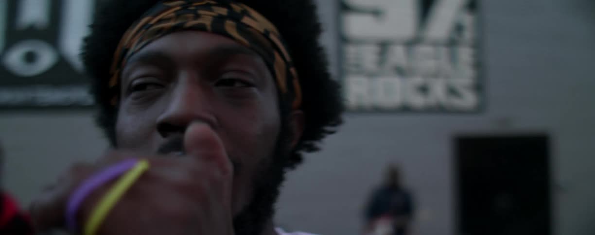 Man talks into a microphone outside of a building in the evening