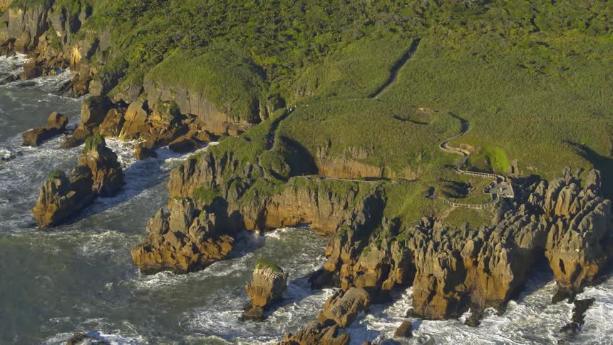 Waves crash over rocks at the base of cliffs