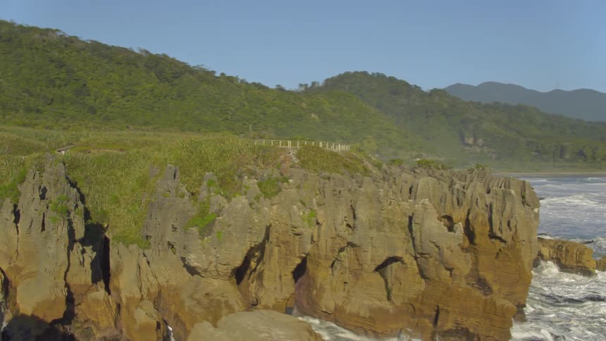 A drone flies towards a lush green covered island