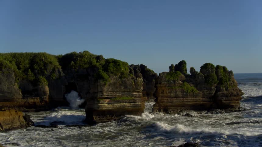 Ocean waves flowing and crashing near rock cliffs