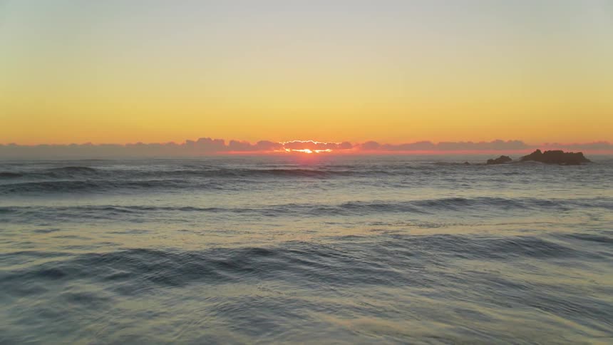 The tide flows towards the shore as the sun sets