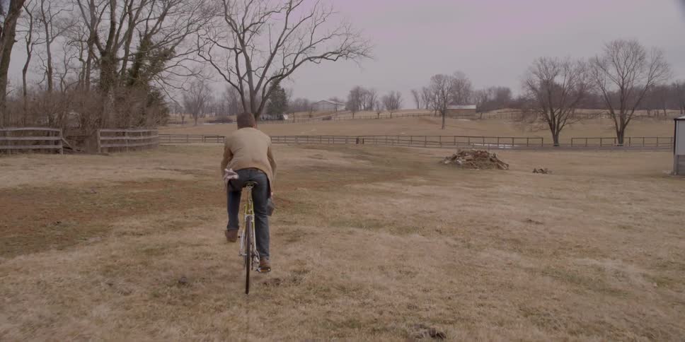 A man is riding his bike across a field