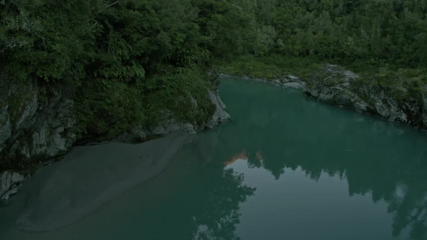 A river reflects its environment as it winds through a gorge during the day