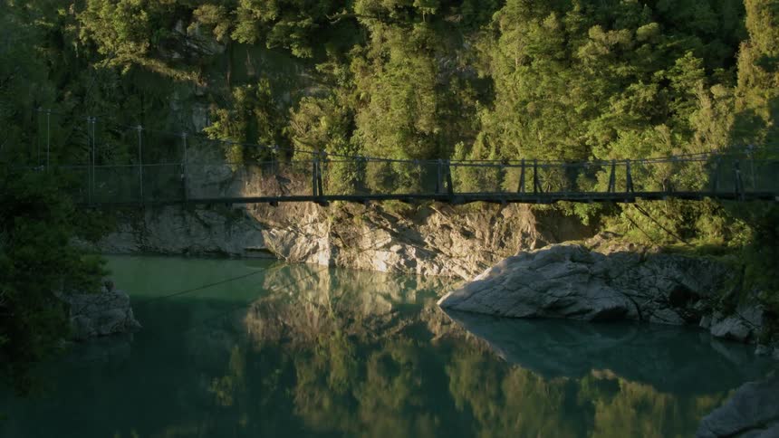 A rope bridge spans a mountain river