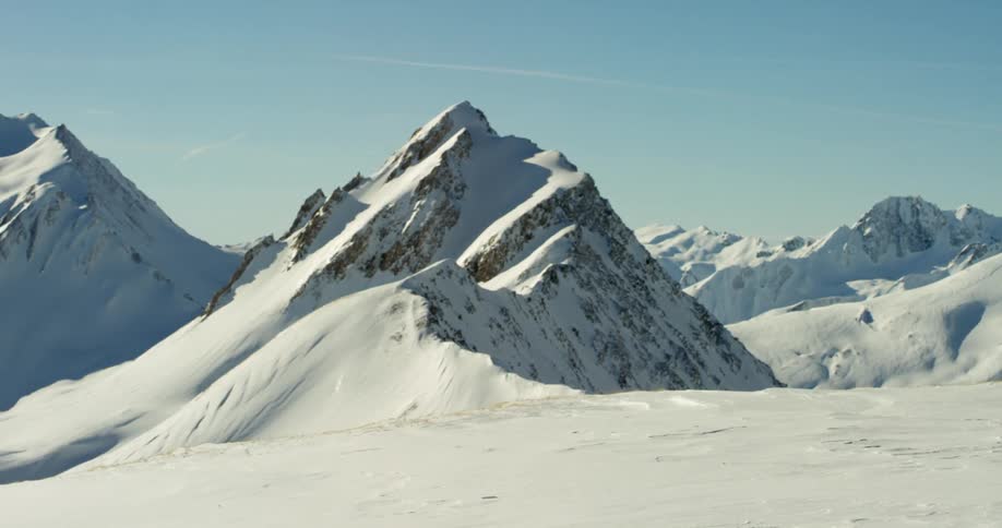 A snow covered landscape with snowy mountains in the distance