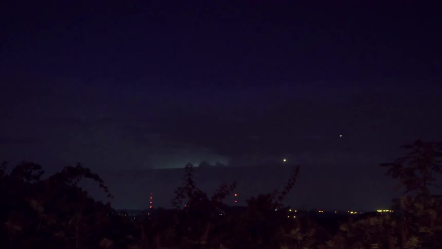 Lightning flashes in the sky at dusk in a community