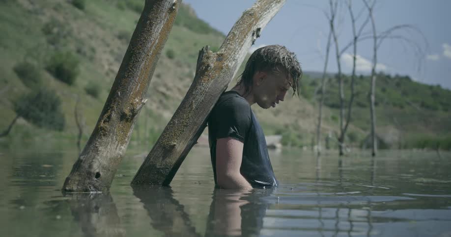 Man stands waist deep in a lake