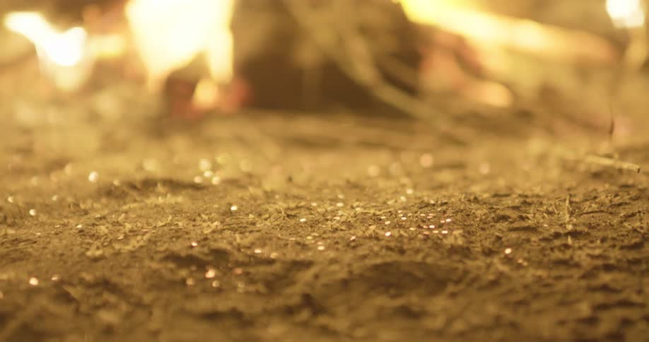 Ash and embers blow around a burning fire