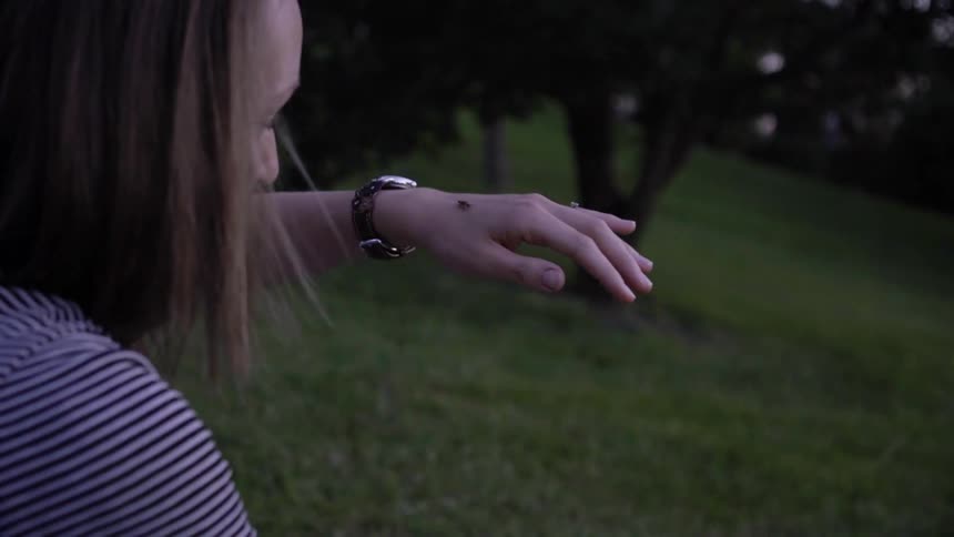A woman watches a firefly on her hand