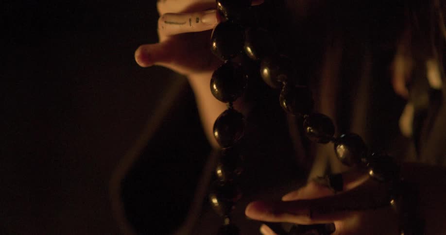 A person is wearing robes and playing with wooden prayer beads
