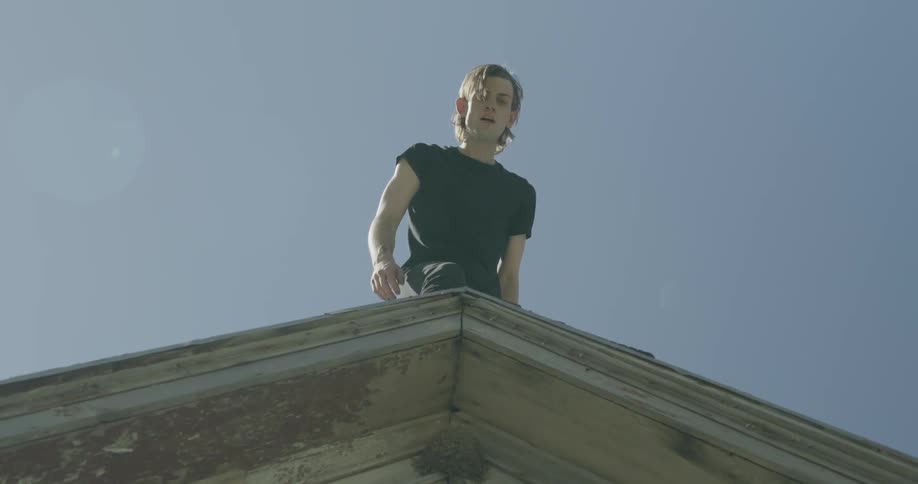 Man standing on the peak of a roof on a clear day