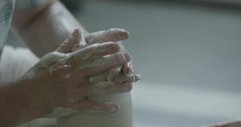 A man is shaping pottery into a vase