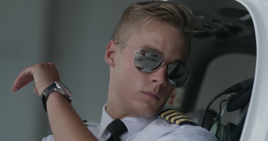 A pilot is getting into the cockpit of a plane and buckling up